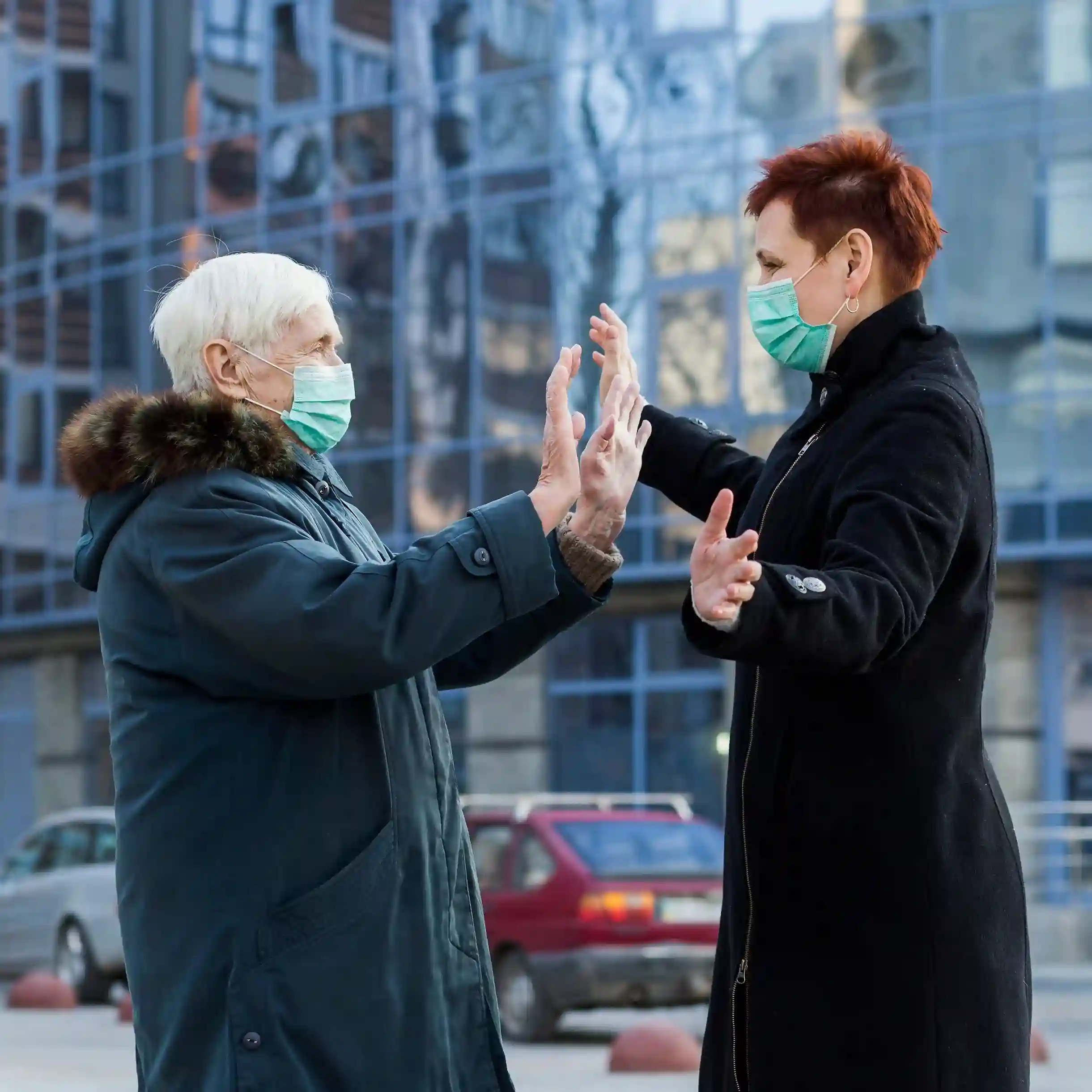 Two elderly women wearing protective masks greeting each other outside a Plano medical facility.