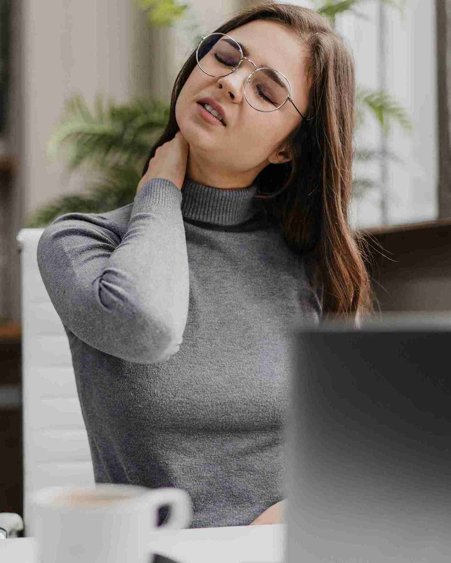 A businesswoman experiencing neck ache while working from home.